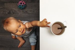 کودکی در حال دست زدن به فنجان قهوه